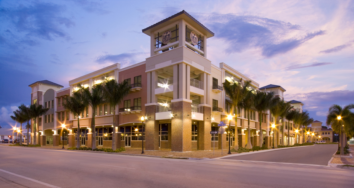 Photo Herald Court Centre three story building surrounded by palm trees at dusk