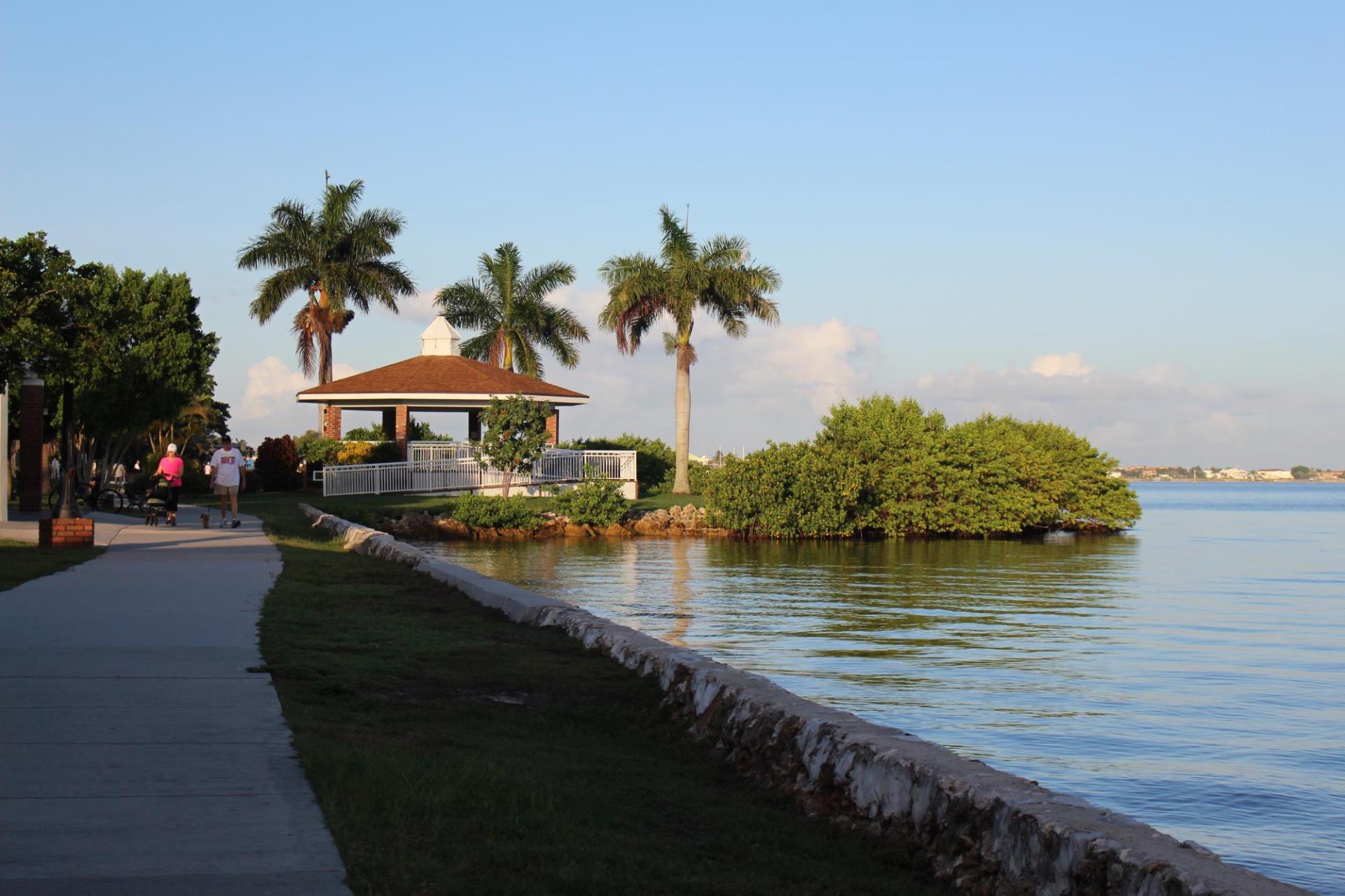 two people walking along gilchrist harbor with gazebo in background