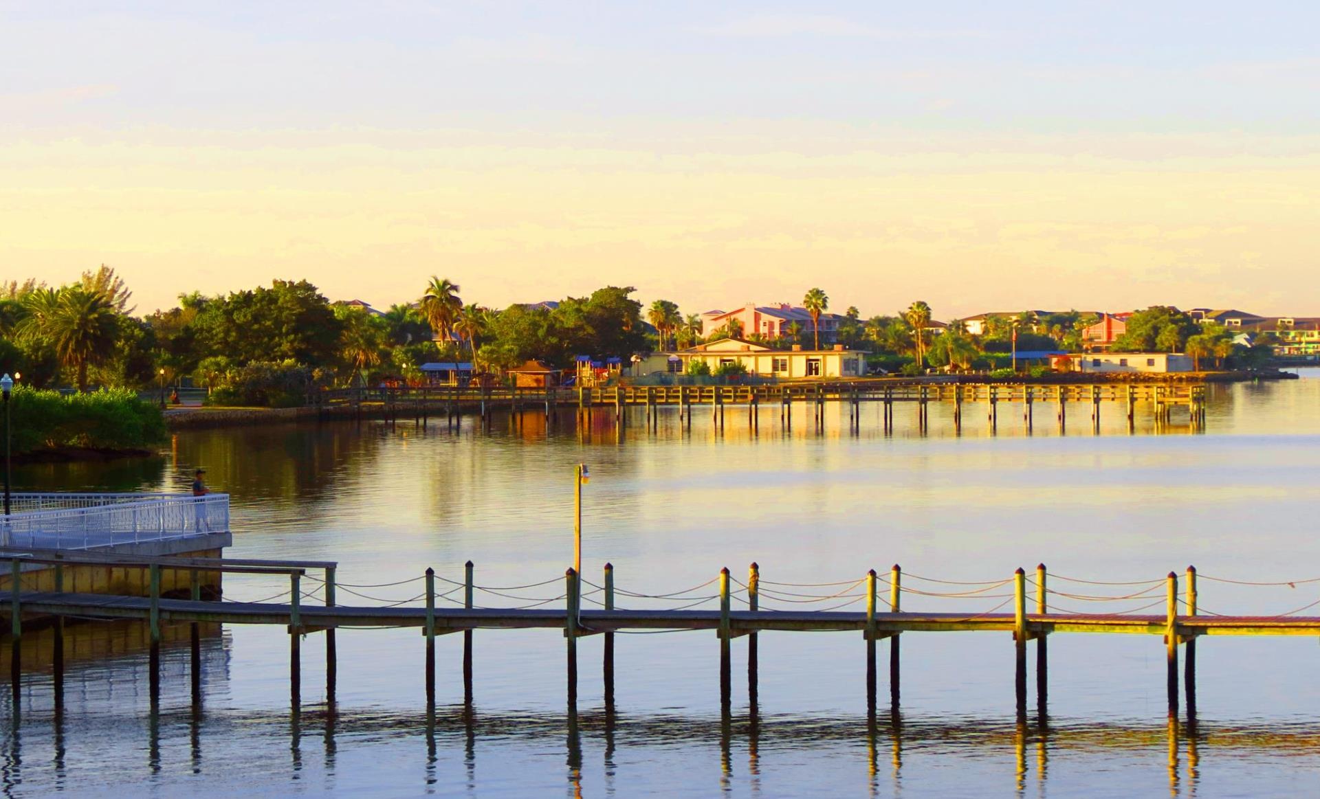 water next to gilchrist park during sunset, docks and houses in background