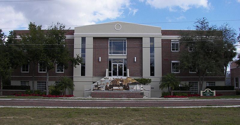 Front view of City Hall Annex building. Brick building with mural painting wall in front of stair access.